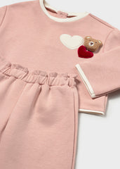 Mayoral A two-piece baby set in dusty pink, featuring a long-sleeve top with white ribbed trim and a teddy bear applique with hearts on the chest, paired with matching cropped pants.