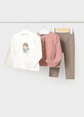A Mayoral children's three-piece clothing set. The set includes an off-white long-sleeve top with a cartoon girl graphic, a dusty pink button-up cardigan with polka dots, and solid taupe-brown pants.