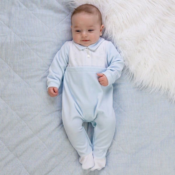 EMILE et ROSE Monty Sumptuous white and blue velour is the fabric of choice for this lovely cosy babygrow. The top of the garment is white with beautifully embroidered, alternate vertical columns of spots, diamonds and crosses. Below the soft blue collar are three pearlised buttons, the rest of the garment is pale blue with contrasting white feet.