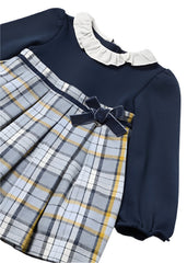 Mayoral toddler girl's long-sleeve dress with a solid navy blue bodice, a white ruffled collar, and a pleated plaid skirt in navy, white, and yellow. A matching navy bow is tied at the waist.