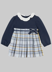 Mayoral toddler girl's long-sleeve dress with a solid navy blue bodice, a white ruffled collar, and a pleated plaid skirt in navy, white, and yellow. A matching navy bow is tied at the waist.