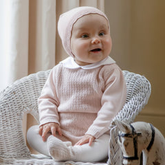 Minny is our new look two-piece, perfect for any occasion. The top is beautifully knitted with a variety of different stitches in a flower pattern. A neat white, pink spot embroidered, scalloped collar and pearlised buttons add additional detailing to this lovely garment. The new style, foot-in leggings have the same textured flower pattern knit on the foot, matching the body of the top. A stretchy waist for baby's comfort and a matching pull on hat completes this cosy set.