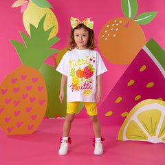 ADEE Trinity short set features an oversized Tutti Frutti print t-shirt, paired with yellow cycling shorts finished with diamante logo on one leg.