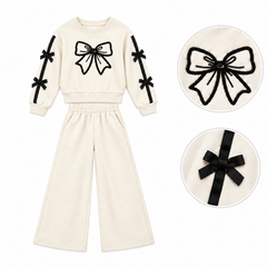Girls cream-colored two-piece tracksuit featuring black sequin bow embroidery on the chest and bows on sleeves.