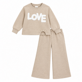 Girls beige knitted two-piece set with LOVE appliqué and pearl detail. Wide-leg bottoms create a relaxed, modern silhouette. Soft coordinating pieces perfect for everyday wear or special occasions.