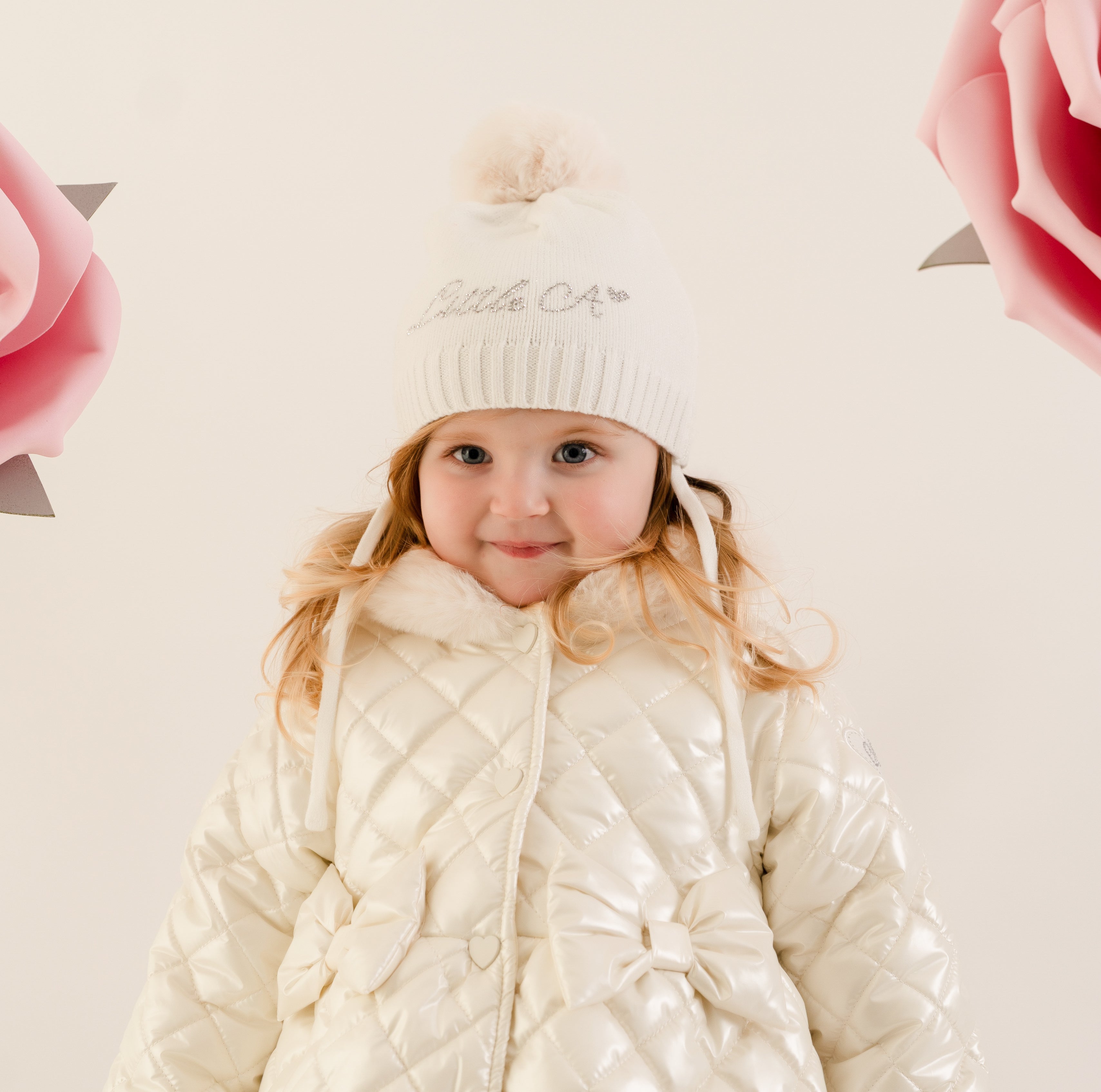 Little A by ADee Little Bloom Collection. The Diamond hat features a knitted design with a soft ribbed finish and a fluffy pom pom on top. Finished with tie fastenings for a snug and secure fit. Snow White