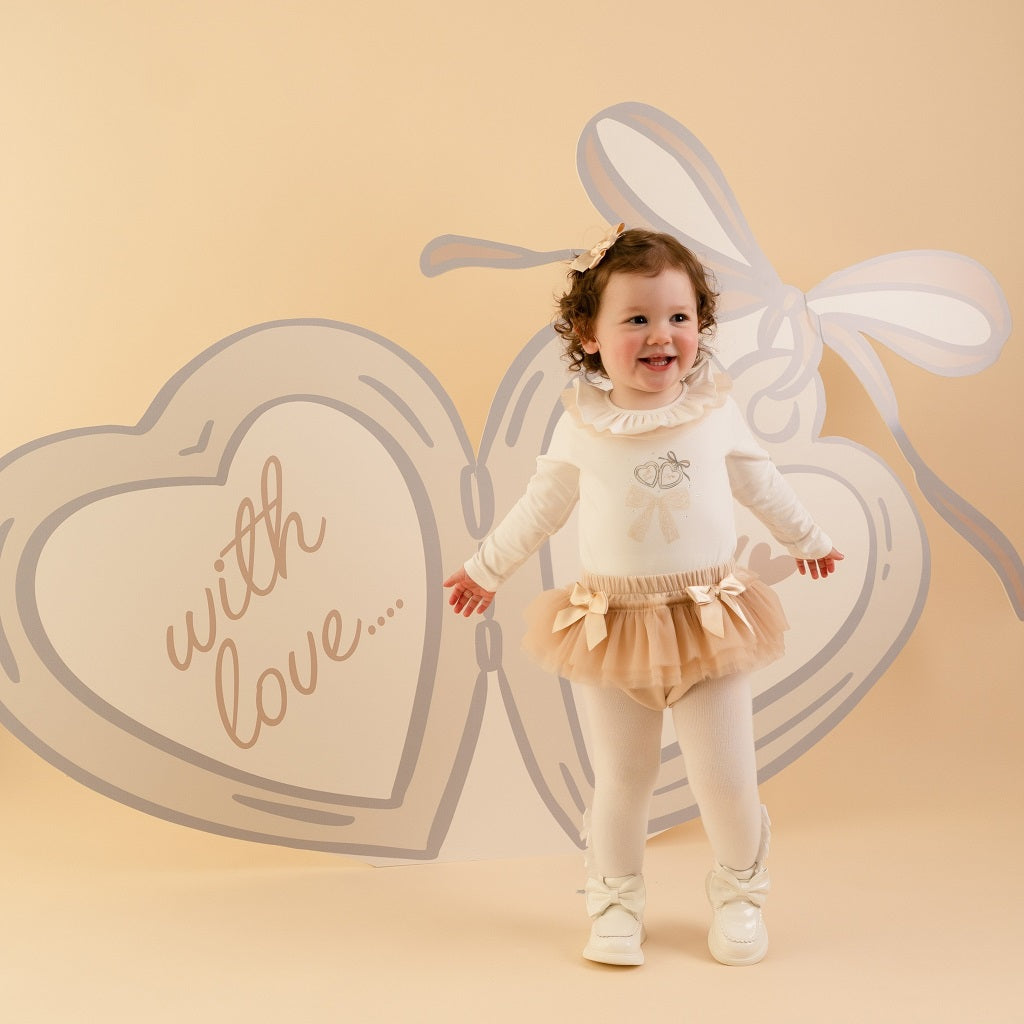 LITTLE A by ADee Little Locket theme. The Emylee jam pant set features a soft long sleeve bodysuit with a delicate heart locket print and frill neckline. Paired with matching tulle frill bloomers, finished with sweet bow details for an extra pretty touch. Snow White/Stone Beige