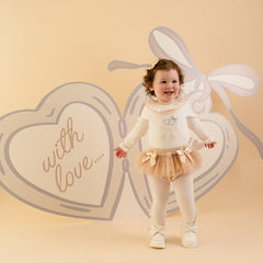 LITTLE A by ADee Little Locket theme. The Emylee jam pant set features a soft long sleeve bodysuit with a delicate heart locket print and frill neckline. Paired with matching tulle frill bloomers, finished with sweet bow details for an extra pretty touch. Snow White/Stone Beige