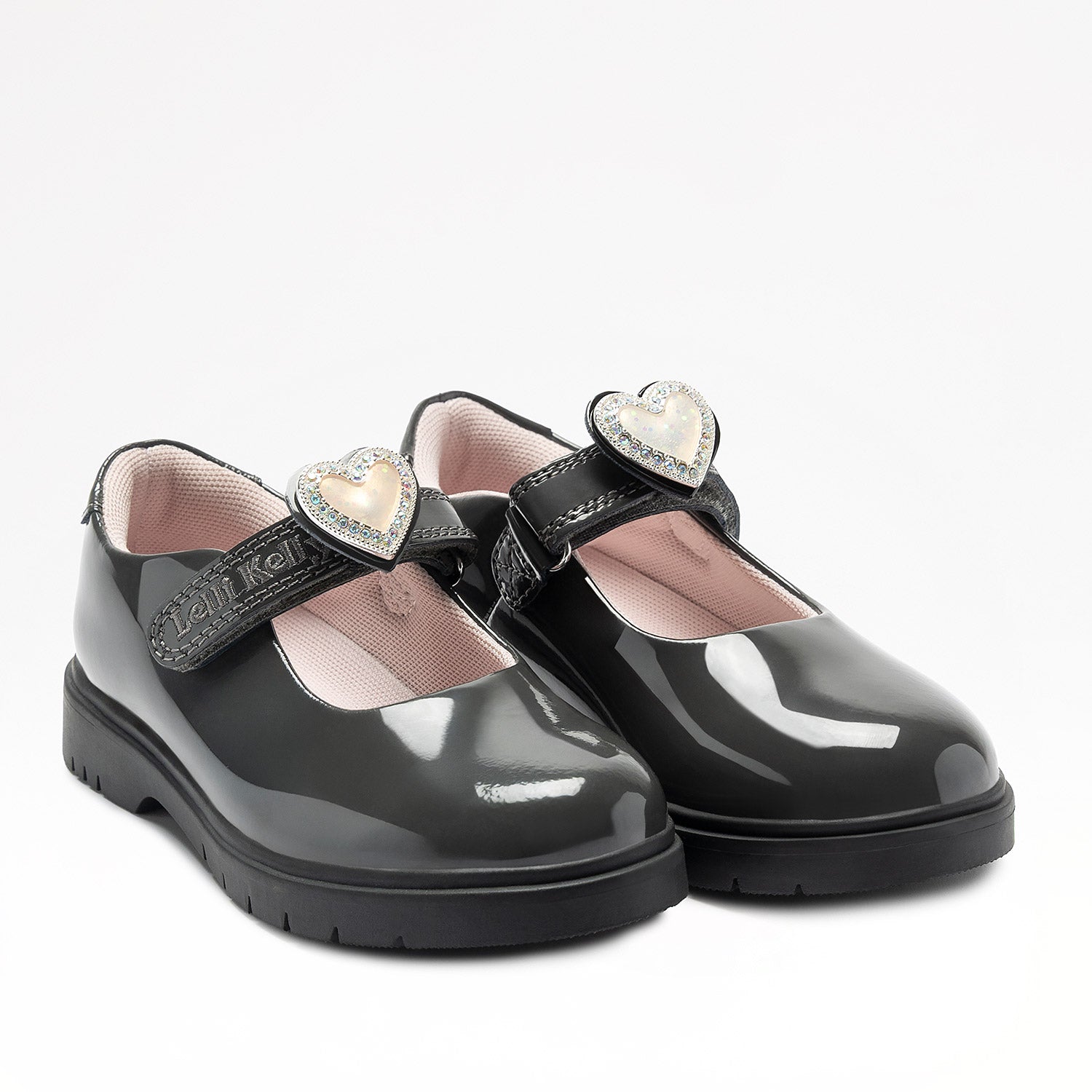 Lelli Kelly Sabrina comes in a grey patent upper. Sabrina has a hook and loop fastening. A large enamel heart with a diamate framed charm, sits on the strap fastening which changes colour in the sunlight. The charm can be slid off and replaced with a large bow. Pink textile lining and chunky sole unit completes the look.