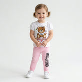 Moschino Baby Girls white teddy t-shirt a with sweet pink jersey leggings with elastic waist, decorated with a black logo on the leg.