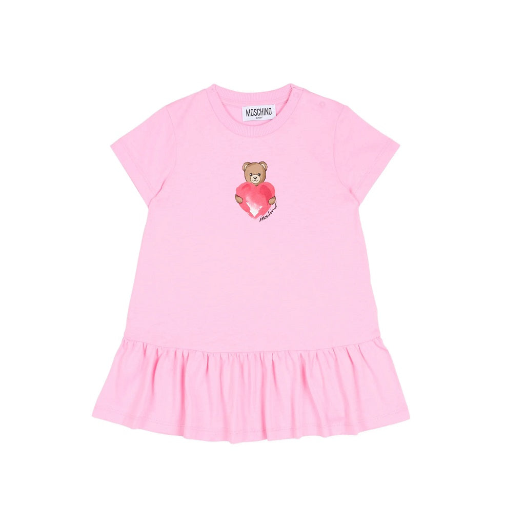 MOSCHINO Baby Girls dress featuring the iconic Teddy Bear clutching a heart. Crafted from soft cotton jersey with short sleeves, dropped waist, and gathered skirt.