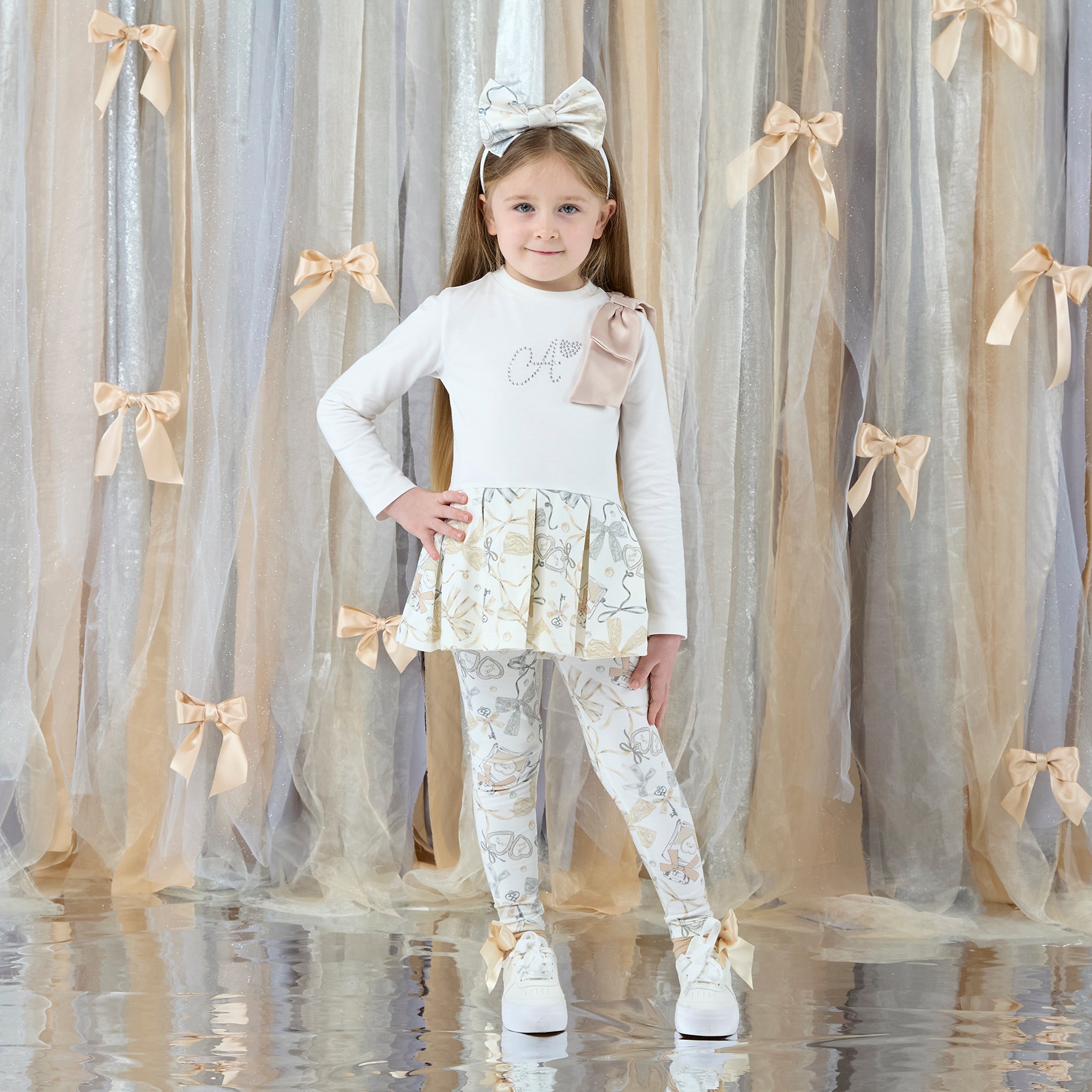 ADEE Eau-de Adee Collection. The Blake legging set features a frill-detail all-over print long-sleeve top with an appliqué shoulder bow and Adee diamante branding, paired with matching printed leggings. Snow White/Beige