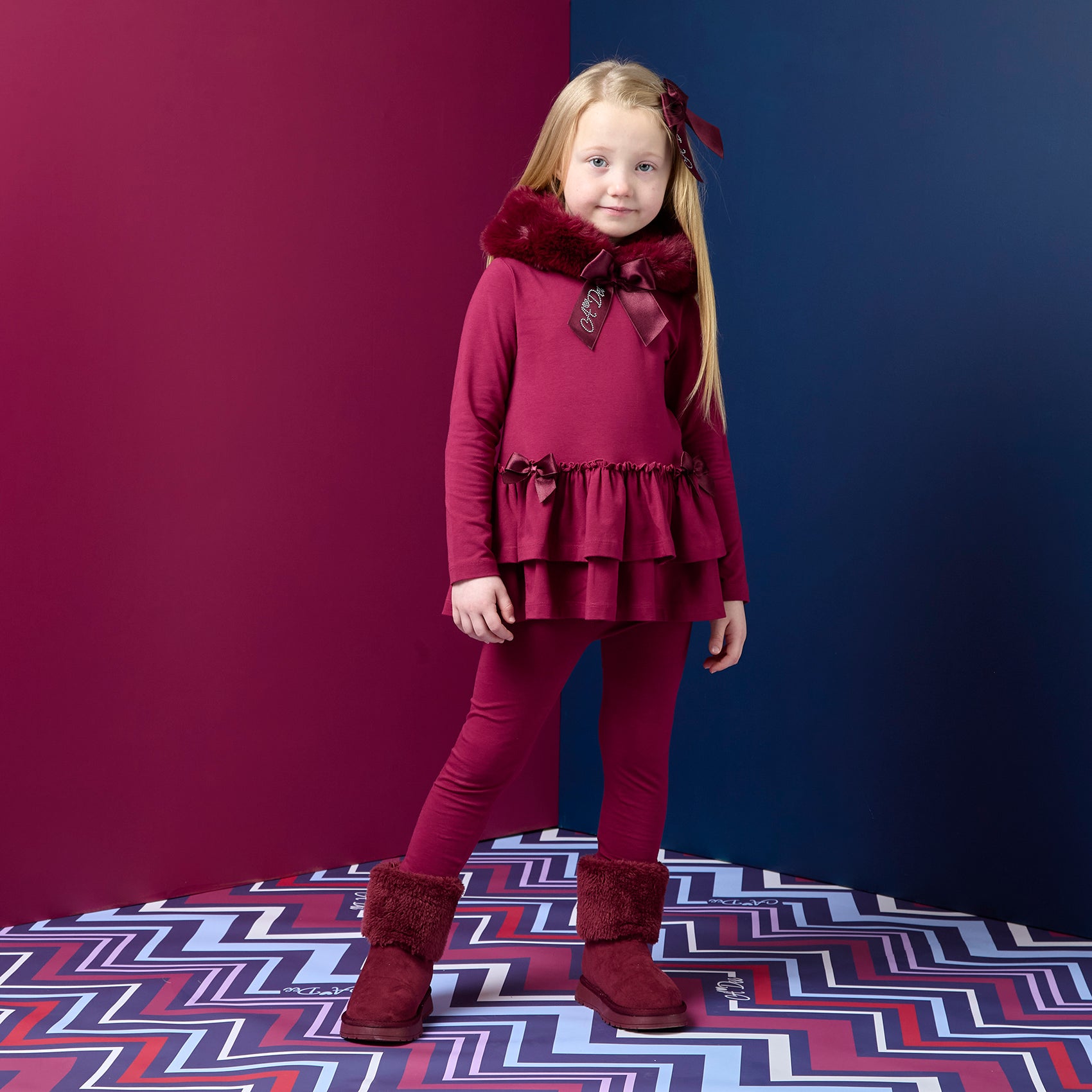 ADEE Chevron Charm Collection. The Alina Legging Set is the perfect addition to your Winter wardrobe! Featuring a fur trimmed hooded top with applique bows and frilled hems. Paired with matching leggings with applique bows at the ankle. Deep Cherry