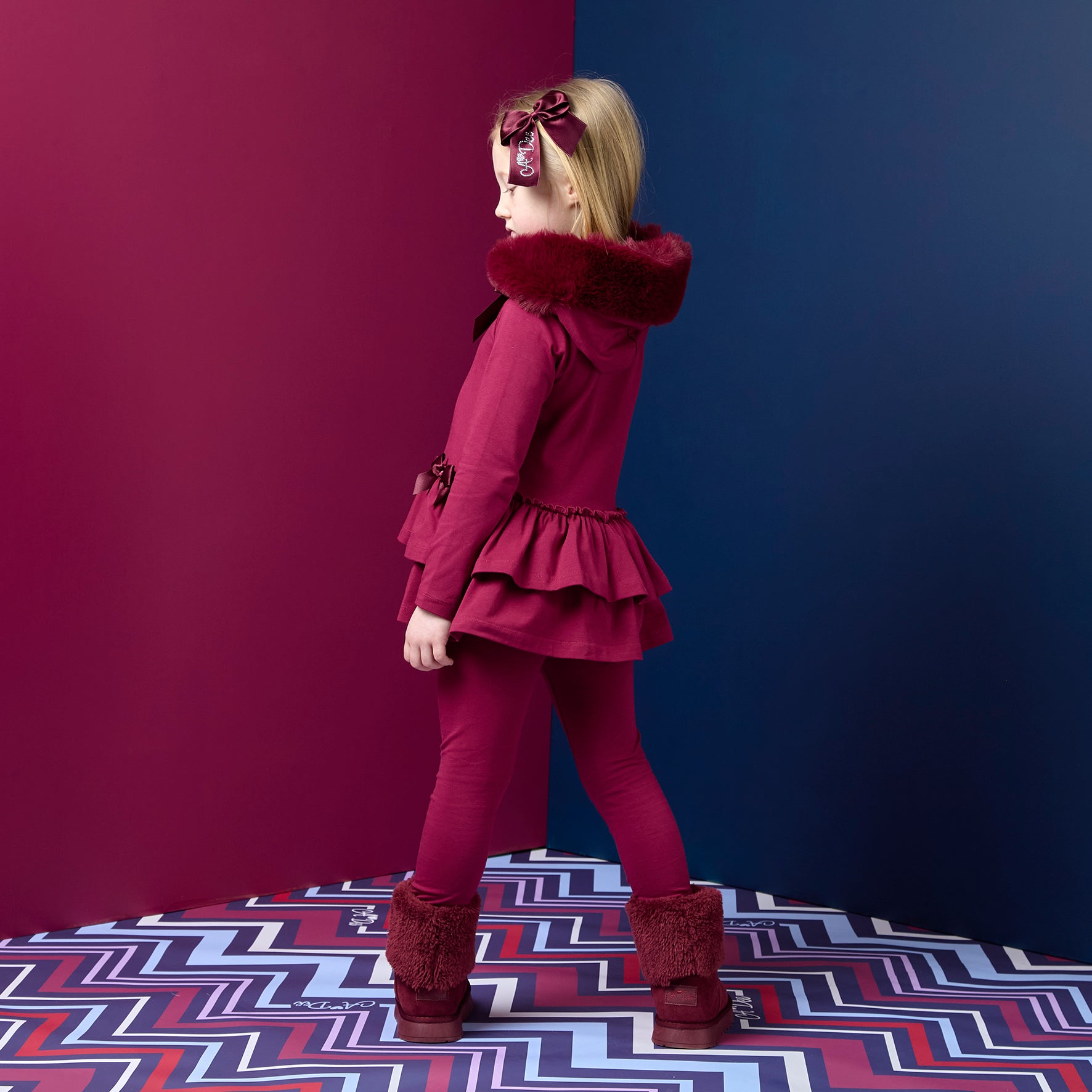 ADEE Chevron Charm Collection. The Alina Legging Set is the perfect addition to your Winter wardrobe! Featuring a fur trimmed hooded top with applique bows and frilled hems. Paired with matching leggings with applique bows at the ankle. Deep Cherry