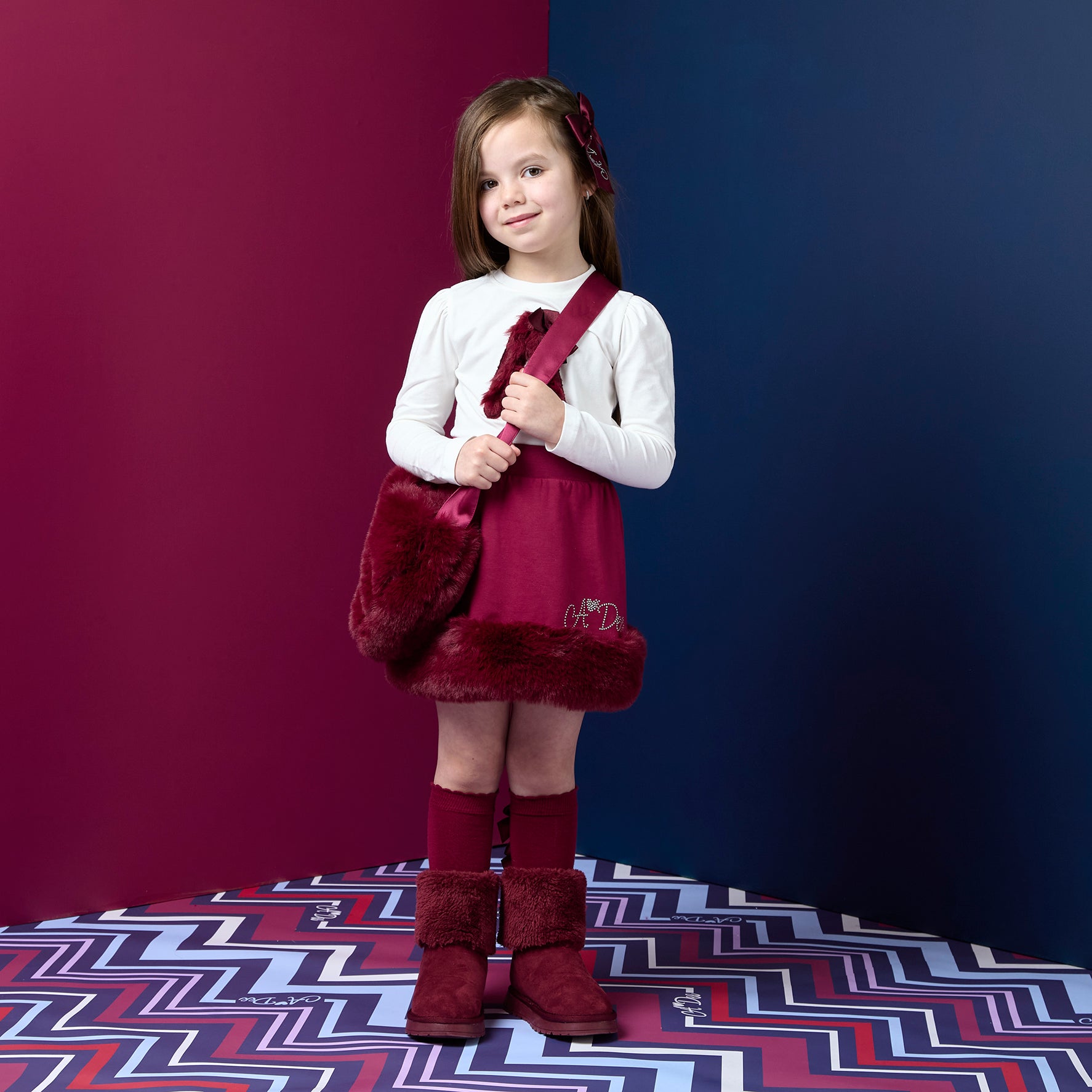 ADEE Chevron Charm Collection. The Andrea Set features a long-sleeved top with gorgeous faux fur “A” artwork on the front, paired perfectly with a red skirt finished with soft faux fur trim. This is a winter wardrobe must have! Snow White/deep Cherry