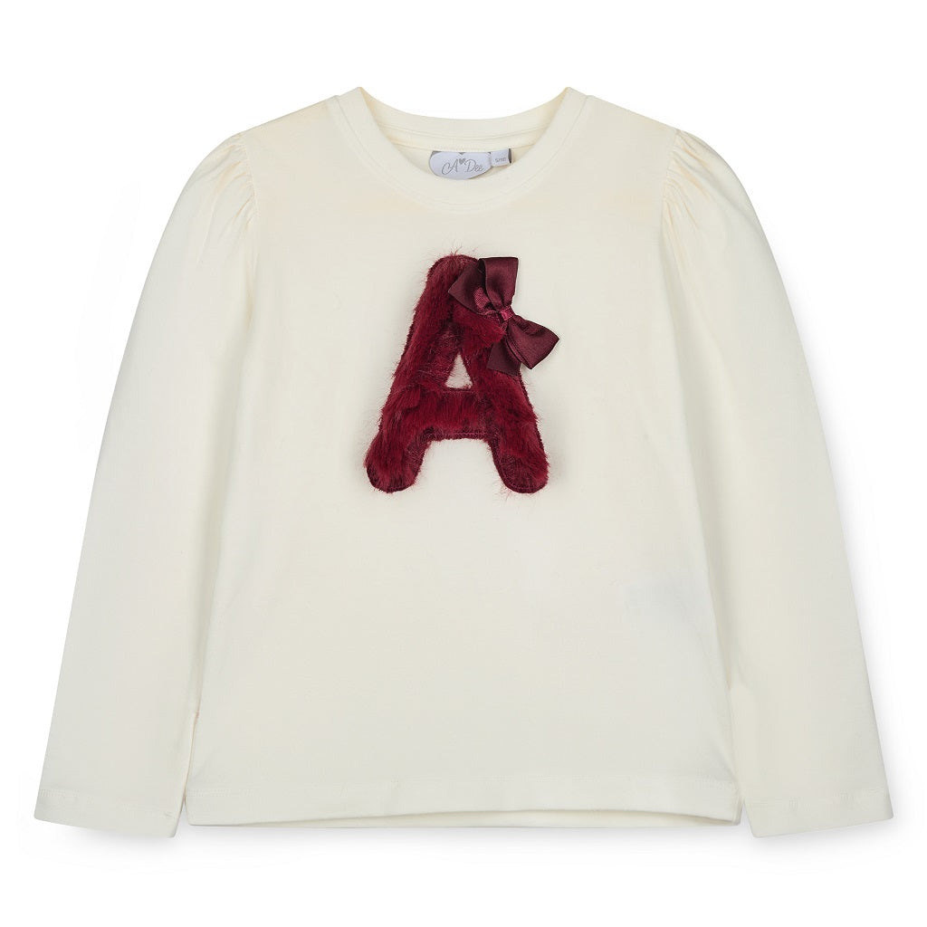 ADEE Chevron Charm Collection. The Andrea Set features a long-sleeved top with gorgeous faux fur “A” artwork on the front, paired perfectly with a red skirt finished with soft faux fur trim. This is a winter wardrobe must have! Snow White/deep Cherry
