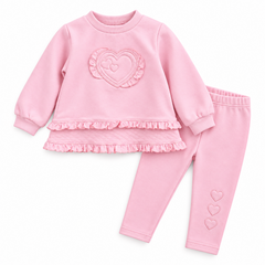 A pink two-piece baby outfit set featuring a long-sleeve top with a large ruffled heart applique on the chest and a matching ruffled hem, paired with matching leggings that have small heart details on the lower leg.