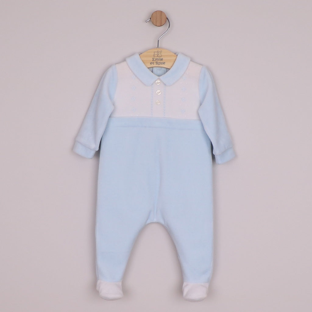 EMILE et ROSE Monty Sumptuous white and blue velour is the fabric of choice for this lovely cosy babygrow. The top of the garment is white with beautifully embroidered, alternate vertical columns of spots, diamonds and crosses. Below the soft blue collar are three pearlised buttons, the rest of the garment is pale blue with contrasting white feet.