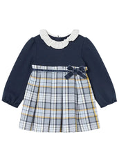 Mayoral  toddler girl's long-sleeve dress with a solid navy blue bodice, a white ruffled collar, and a pleated plaid skirt in navy, white, and yellow. A matching navy bow is tied at the waist.