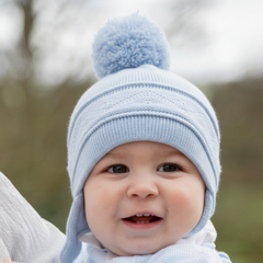 EMILE et ROSE Griffin - Baby blue knitted helmet-shaped hat with ear flaps and small pompoms trimming the ends of the ties below each ear. The main feature is the fun, over-size pompom on the top!