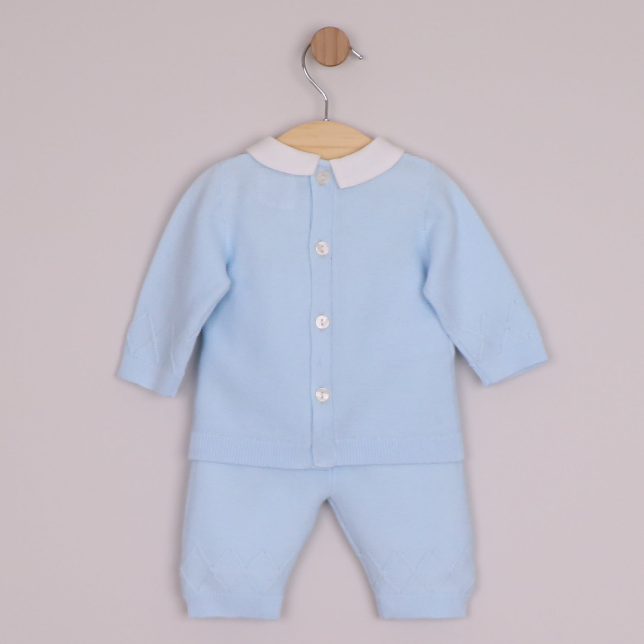 EMILE et ROSE Malachi soft knitwear in a pale blue knitted two piece. The main feature of this style is a textured criss-cross design across the chest. This pattern continues around the sleeves and the ankle of the leggings. Finishing touches include a crisp white collar, pearlised buttons , all topped off with a cute coordinating hat.