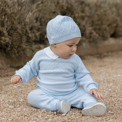 EMILE et ROSE Malachi soft knitwear in a pale blue knitted two piece. The main feature of this style is a textured criss-cross design across the chest. This pattern continues around the sleeves and the ankle of the leggings. Finishing touches include a crisp white collar, pearlised buttons , all topped off with a cute coordinating hat.