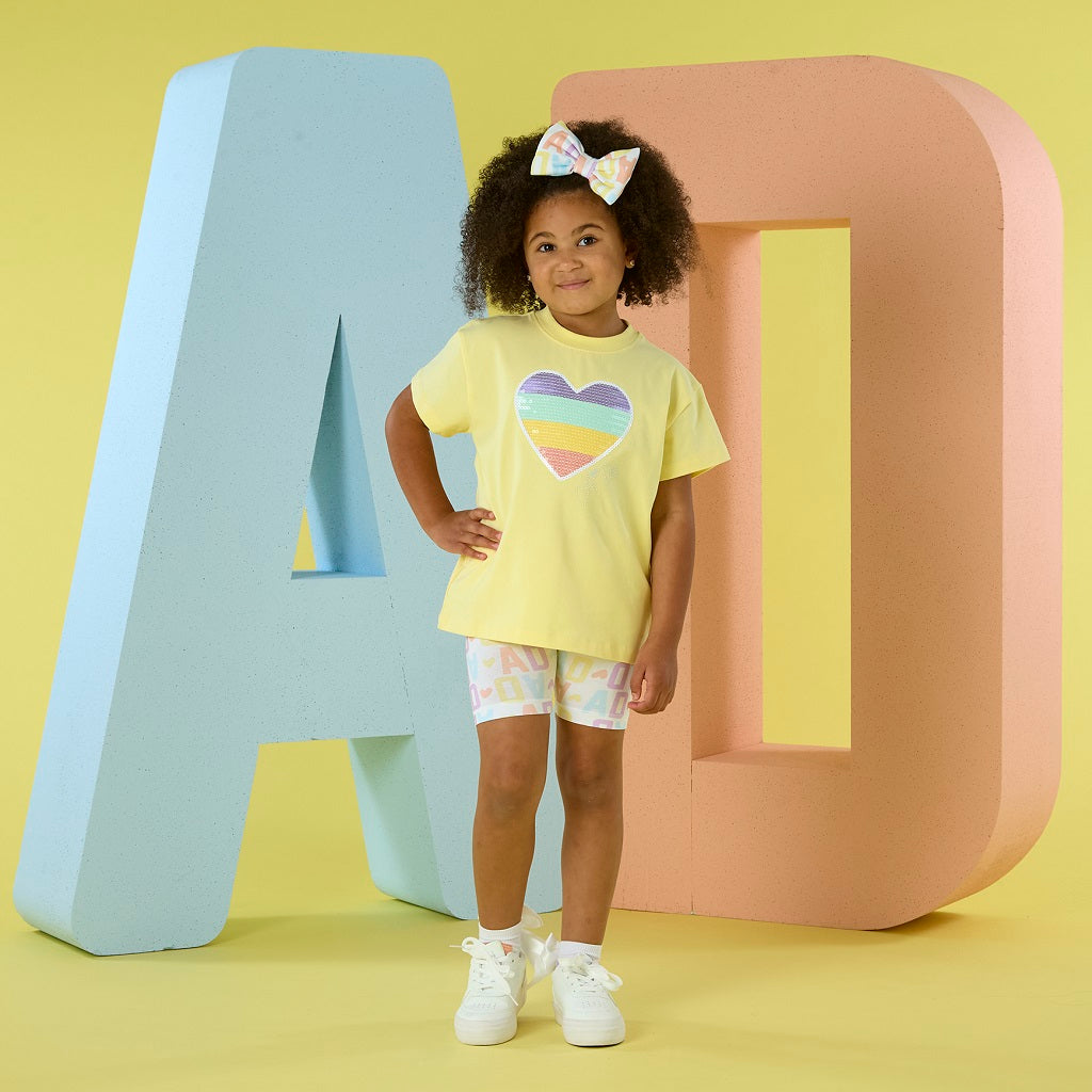 ADEE Signature Summer The Saz cycling short set features an oversized t-shirt with a sequined heart artwork on the front. Paired with initial print cycling shorts