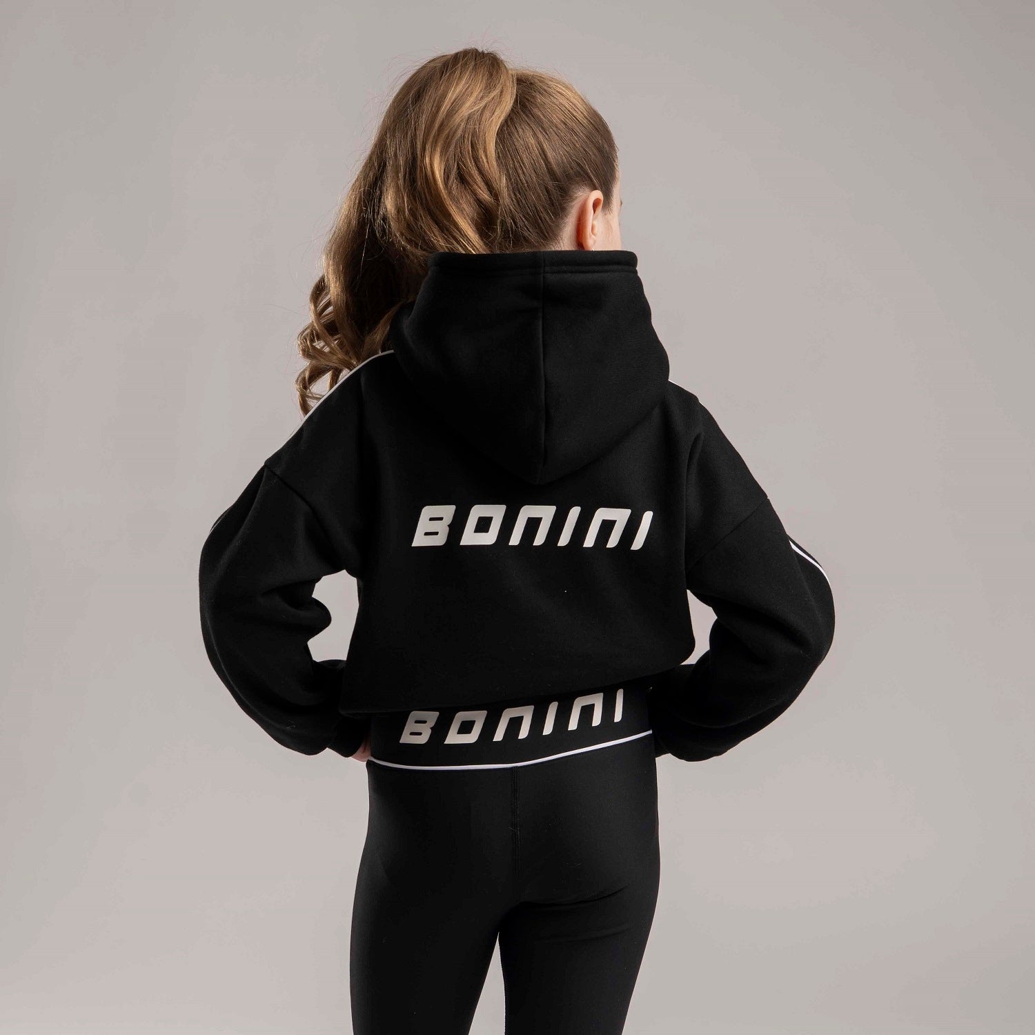 BONINI by ADee The Revive Hoodie features a relaxed fit with a cropped silhouette. Finished with signature Bonini branding, it’s perfect for layering or pairing with matching pieces for an effortless everyday look. Black