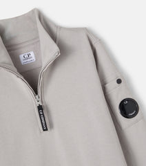 C.P. Company boys' U16 diagonal fleece half zip closure, high neck sweatshirt with iconic lens detail, ribbed texture, and reinforced cuffs and hem. 