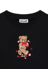 Black crewneck sweatshirt for girls by the luxury Italian designer Moschino. Made from soft cotton, features the brands iconic Teddy Bear with red hearts and logo print on the front.