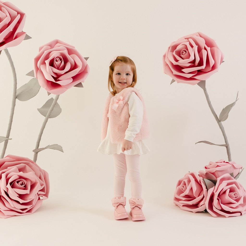 LITTLE A by ADee Little Bloom theme. The Dani gilet features ultra-soft faux fur, a cosy sleeveless design, and a sweet bow detail at the front. Pale Pink