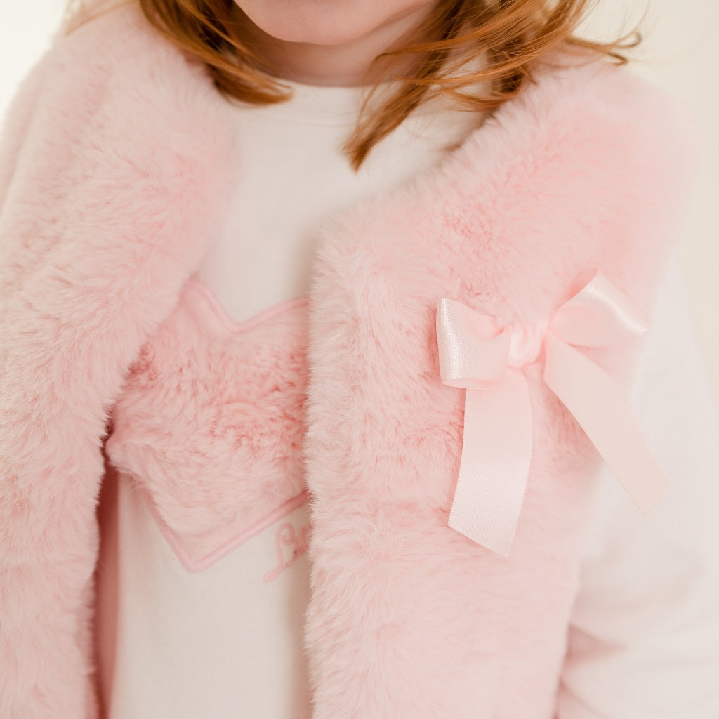 LITTLE A by ADee Little Bloom theme. The Dani gilet features ultra-soft faux fur, a cosy sleeveless design, and a sweet bow detail at the front. Pale Pink