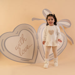 LITTLE A by ADee Little Locket theme. The Demi legging set features a long sleeve jumper top with a sweet heart detail and peplum frill hem, paired with soft leggings finished with a subtle motif. A comfy and cute everyday outfit. Snow White/Stone Beige