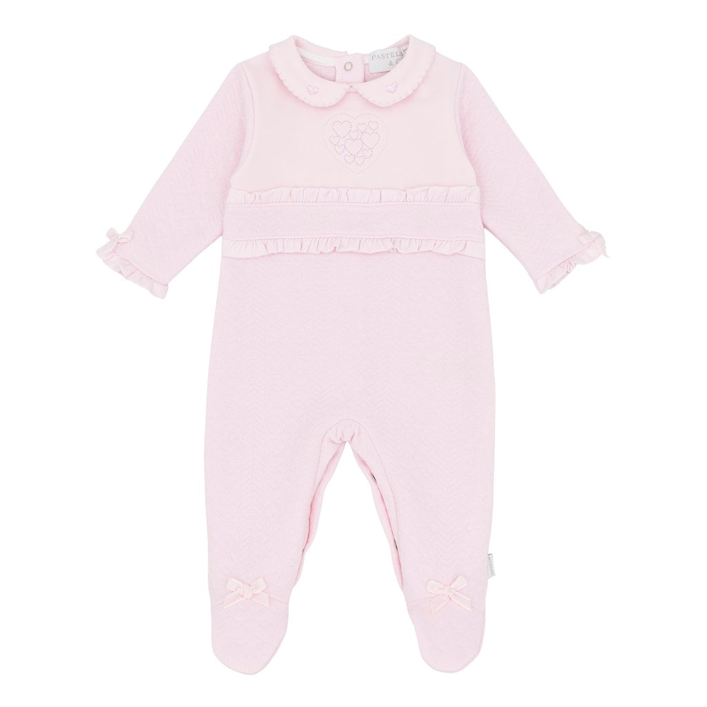 Pastels & Co - Hearts & Bows Story. The Olivia all-in-one in soft pale pink offers timeless elegance for baby girls.