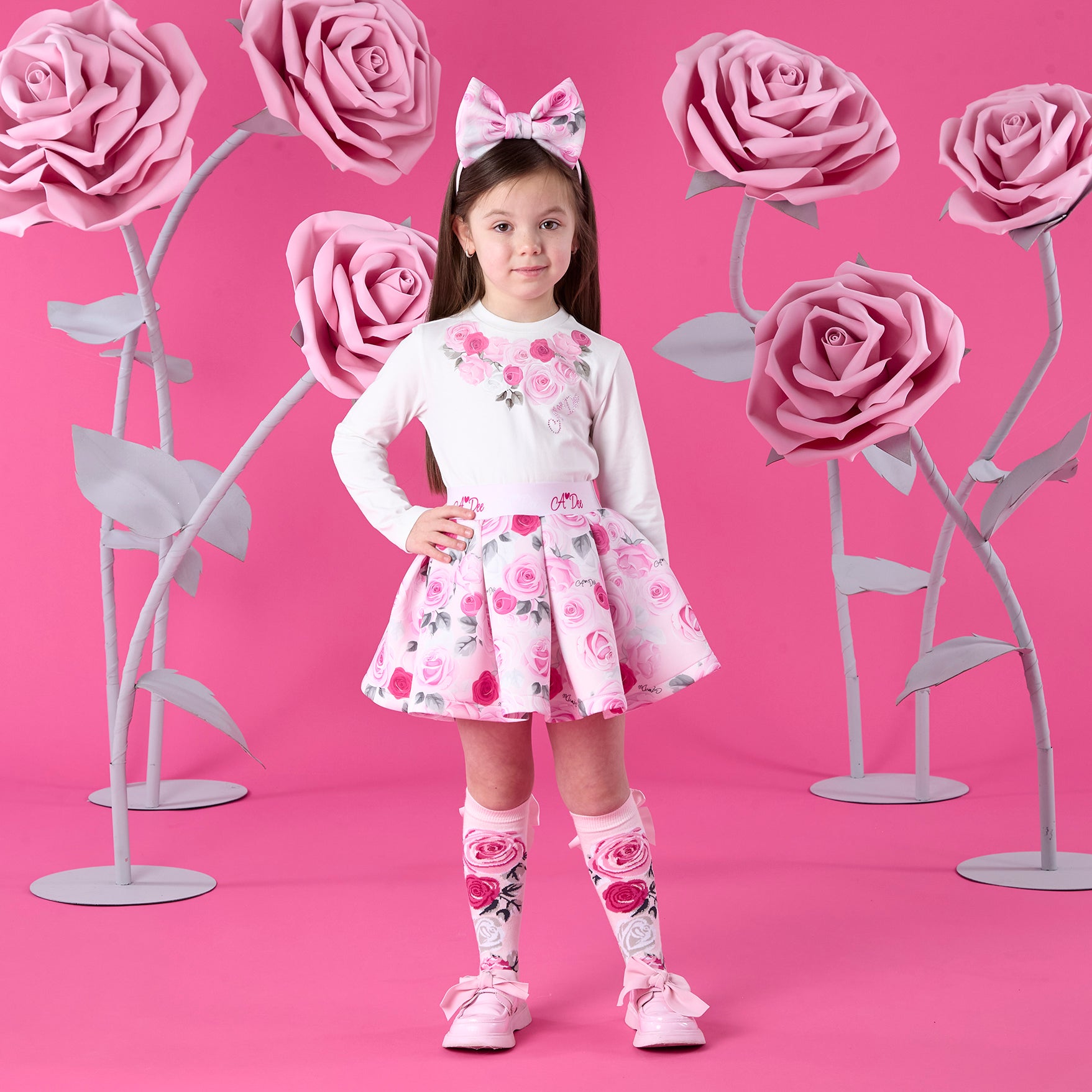 ADEE Winter Bloom Collection. The Ariella Set includes a long-sleeved top featuring beautiful roses artwork on the front, paired with a matching pleated rose-print skirt finished with a branded waistband