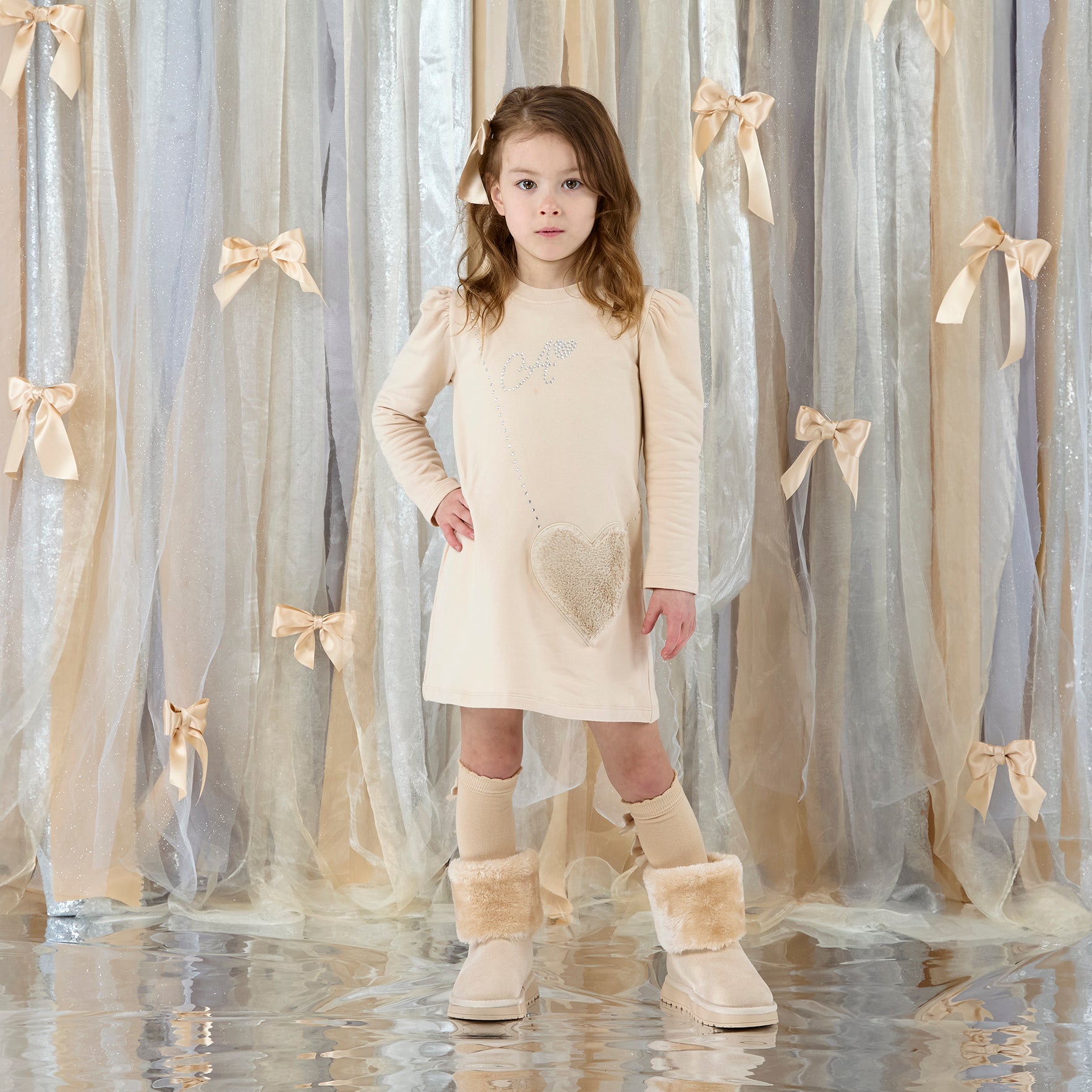 ADEE Eau de theme. The Alyssa dress features a faux fur applique handbag artwork, finished with a classic A*Dee diamanté logo. Stone Beige