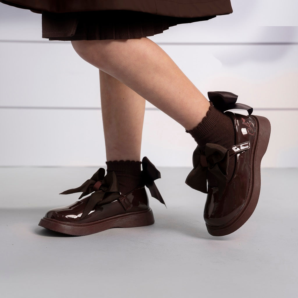 ADEE The Lyra shoe is perfect for school, with pretty bows on the velcro strap and embroidered logo to the side. Finished with non-slip rubber soles. Brown.
