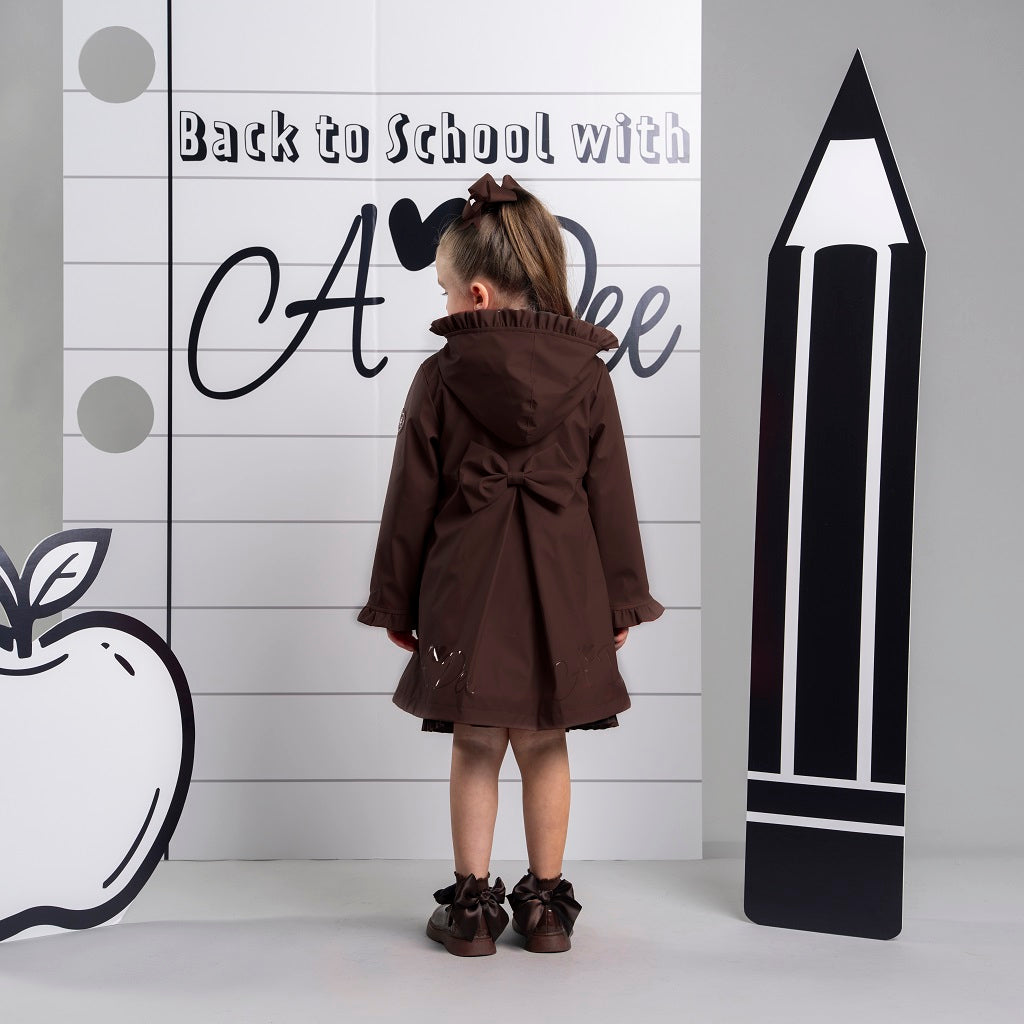 ADEE BTS The Nova is the must-have back to school raincoat! It features front and back pleats with pretty bow detailing, branding around the hem and frills at the cuffs and hood. Complete with a silver reflective logo badge on one arm and a silver branded puller. Brown