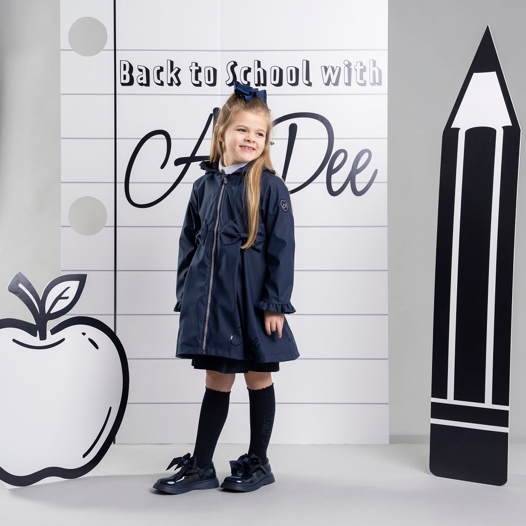 ADEE BTS The Nova is the must-have back to school raincoat! It features front and back pleats with pretty bow detailing, branding around the hem and frills at the cuffs and hood. Complete with a silver reflective logo badge on one arm and a silver branded puller. Dark Navy