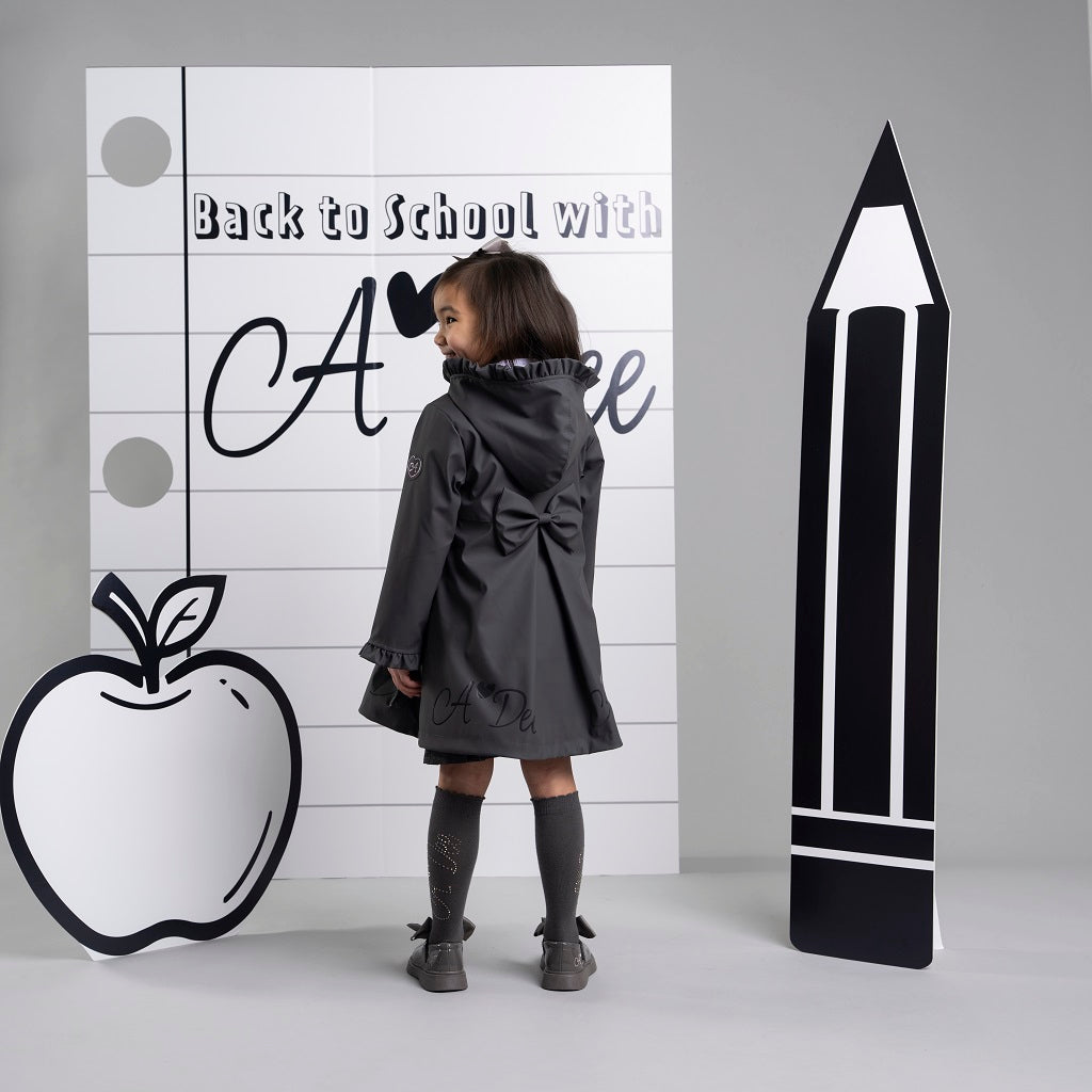 ADEE BTS The Nova is the must-have back to school raincoat! It features front and back pleats with pretty bow detailing, branding around the hem and frills at the cuffs and hood. Complete with a silver reflective logo badge on one arm and a silver branded puller. Dark Grey
