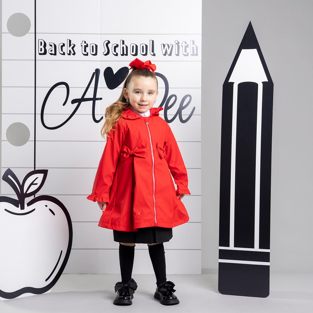ADEE The Nova is the must-have back to school raincoat! It features front and back pleats with pretty bow detailing, branding around the hem and frills at the cuffs and hood. Complete with a silver reflective logo badge on one arm and a silver branded puller. Red