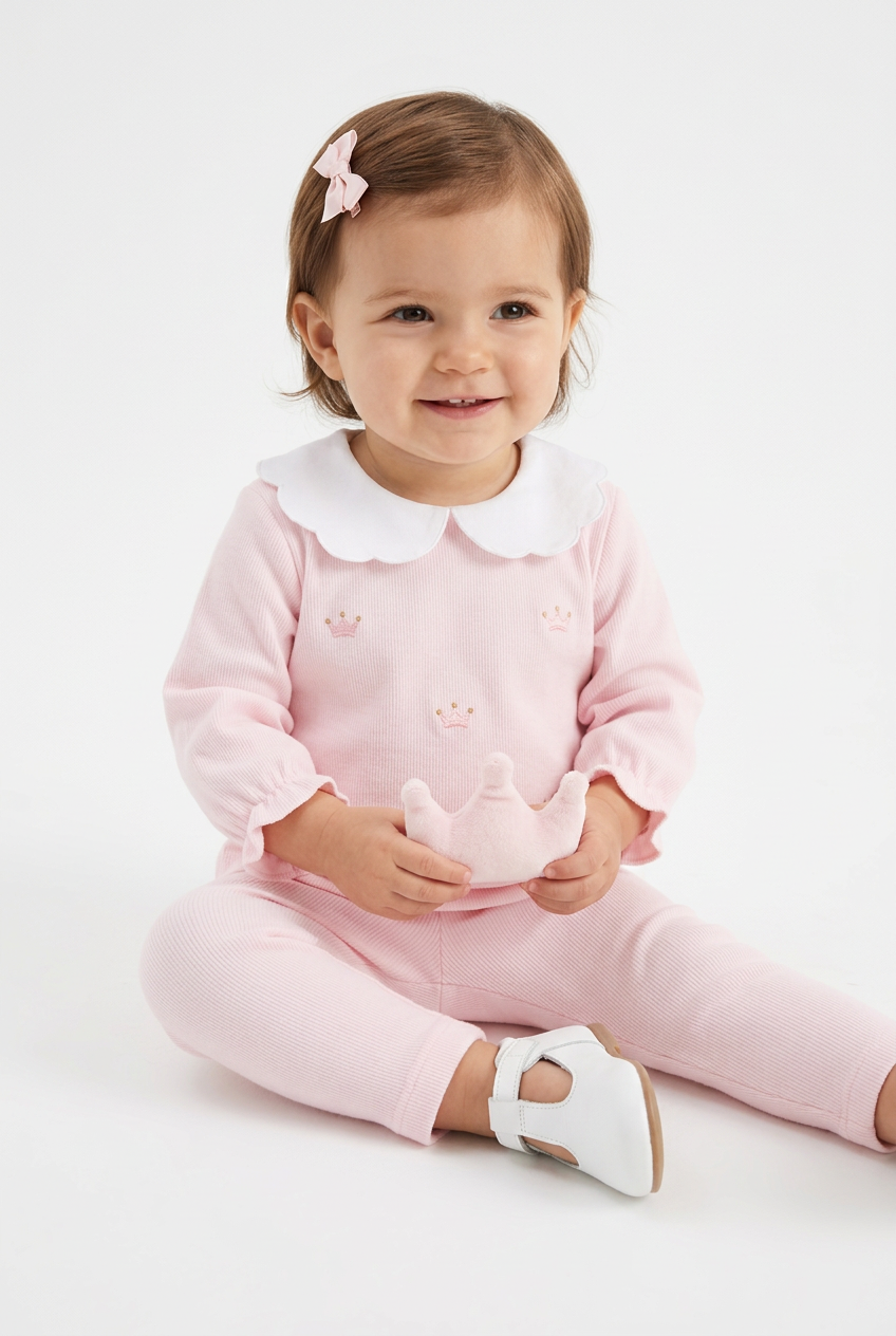 Luxurious 2 piece trouser set handcrafted in Peru with charming embroidered crowns motif in pale pink and gold. Perfect for keeping baby cosy day and night. A special gift for a new baby girls from the Adriana Mae Rosa Reale Collection.